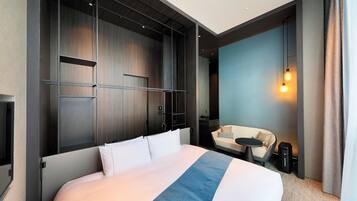 Quarto de hotel moderno com uma cama grande, uma escrivaninha e uma área de estar.