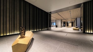 A spacious lobby with a modern design, featuring a wooden reception desk, a decorative vase, and a seating area with a unique light fixture. - Richmond Hotel Premier Kyoto Shijo (Kyoto)