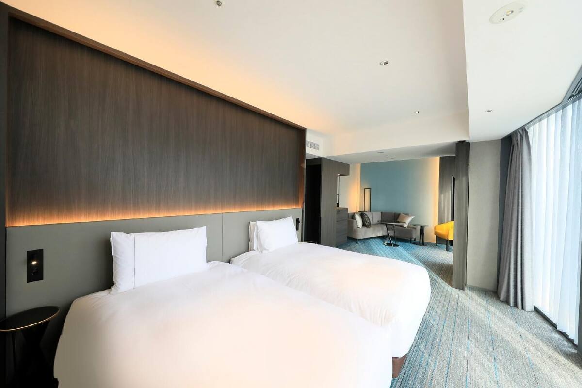 A hotel room with a large bed, a desk, a chair, and a sofa.