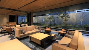 A modern lounge area with sofas, tables, and chairs arranged around a large window overlooking a garden. - Richmond Hotel Premier Kyoto Shijo (Kyoto)