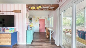 Une cuisine chaleureuse avec une table et des chaises en bois, une porte rose et une vue sur une terrasse.