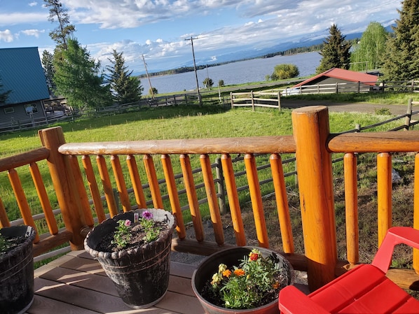 A wooden deck with a railing overlooking a lake and mountains. - Gorgeous Lake view log cabin near Tamarack ski resort (Donnelly)
