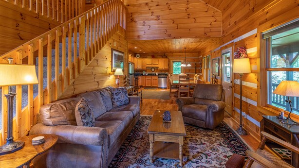 A log cabin interior with a living room, a staircase, a kitchen, and large windows. - Amen Corner - Close to Boone! Hot Tub, Pet Friendly, Ping Pong, Foosball, Mountain Views (Vilas)