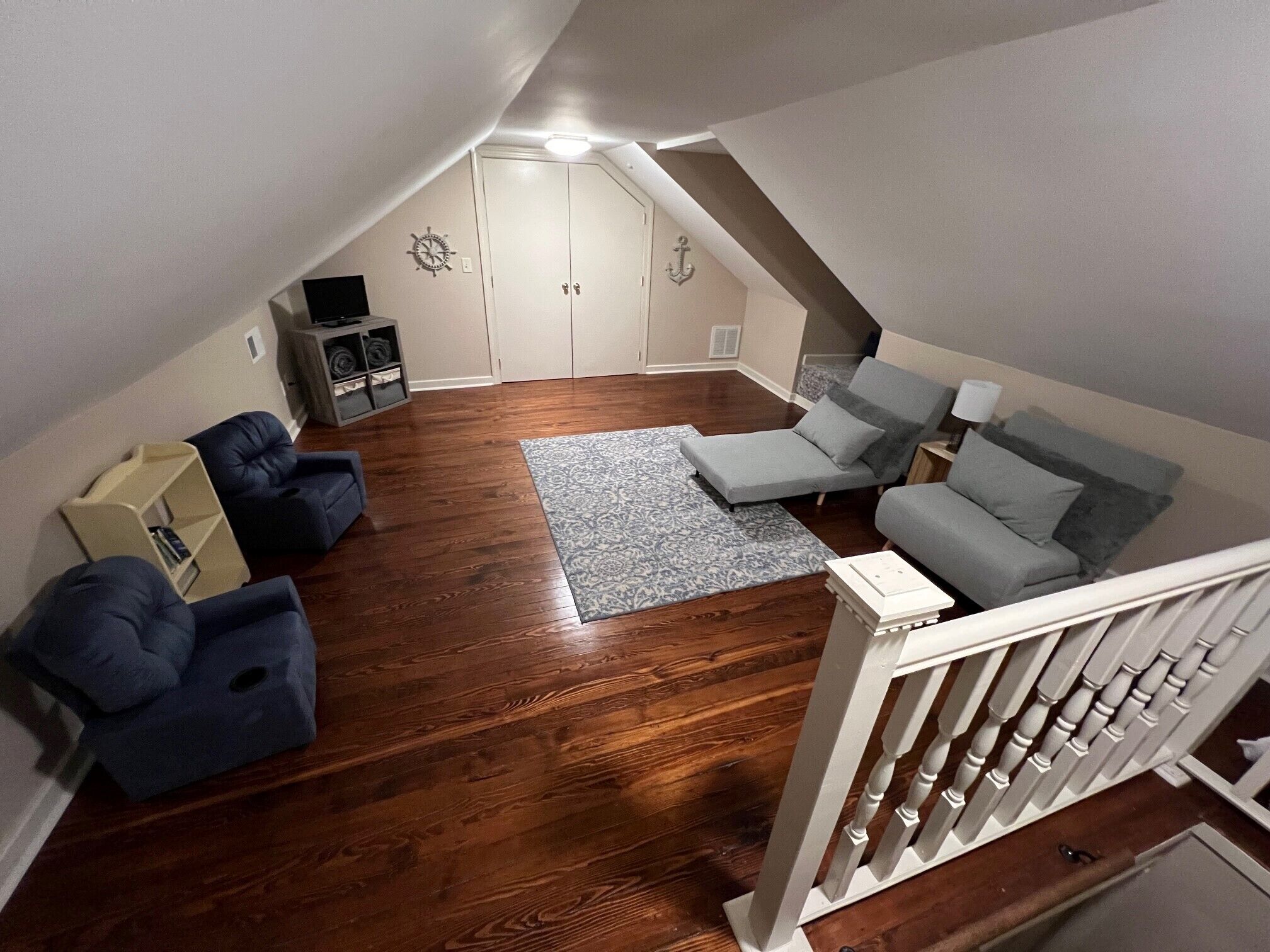 A loft-style living room with a wooden floor, a gray patterned rug, and a gray sofa.