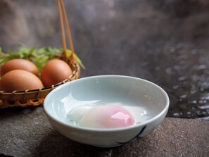 A bowl with a raw egg, a basket of eggs, and a blurred background.