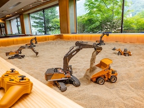 A model construction site with various toy vehicles and a sandbox.