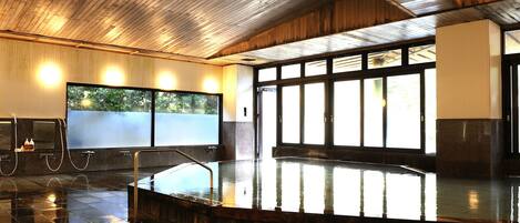 Una amplia piscina interior con techo de madera y grandes ventanales que dejan entrar la luz natural.