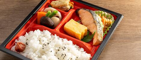 A bento box with rice, fish, vegetables, and tofu.