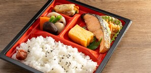 A bento box with rice, fish, vegetables, and tofu.