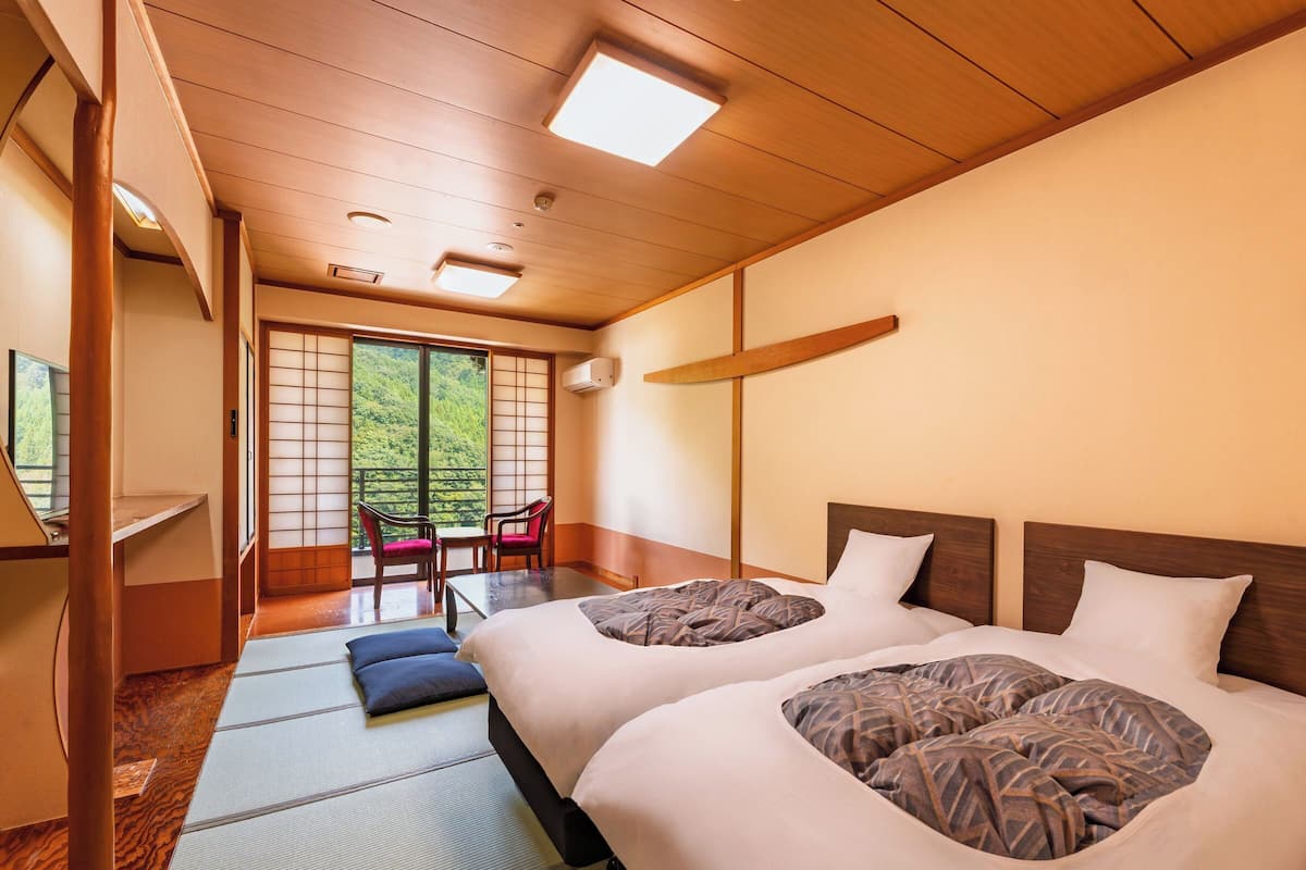 Une chambre d’hôtel avec un grand lit, un bureau et une vue sur un balcon équipé de chaises.