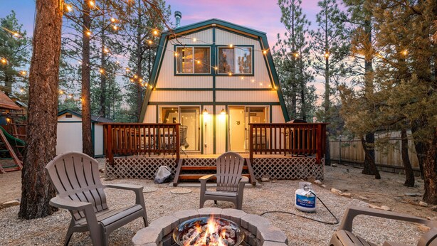 Een chalet met een terras, een vuurkorf en twee Adirondack stoelen.