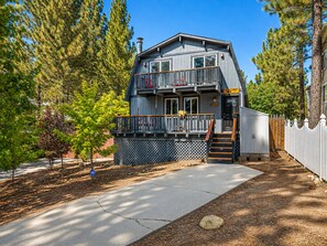 A two-story building with a balcony, a wooden deck, and a fenced yard.