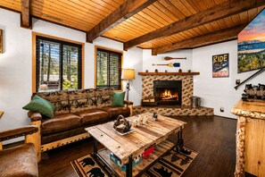 A cozy living room with a fireplace, wooden furniture, and a scenic view. - Bear PAC Hideout - Walk to Village, Fireplace, Game Room, Pool Table (Big Bear Lake)