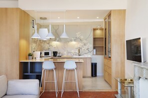 A modern kitchen with a central island, bar stools, a microwave, and a coffee machine. - SUITE ROI RENE (Aix-en-Provence)
