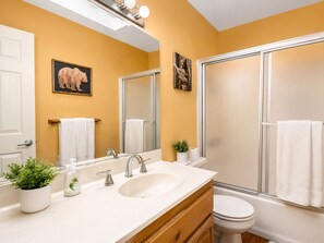 A bathroom with a white sink, two mirrors, a shower, and a toilet.