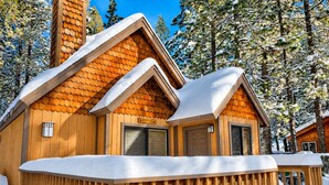 Una baita di legno con tetto innevato e veranda in legno.