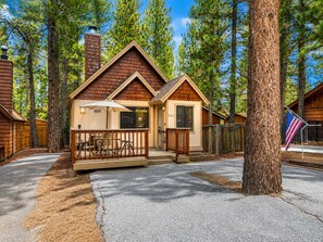 A cabin with a porch, outdoor seating, and a flag. - Moonridge Heaven - Close to Slopes, Fireplace, Deck, Barbecue (Big Bear Lake)