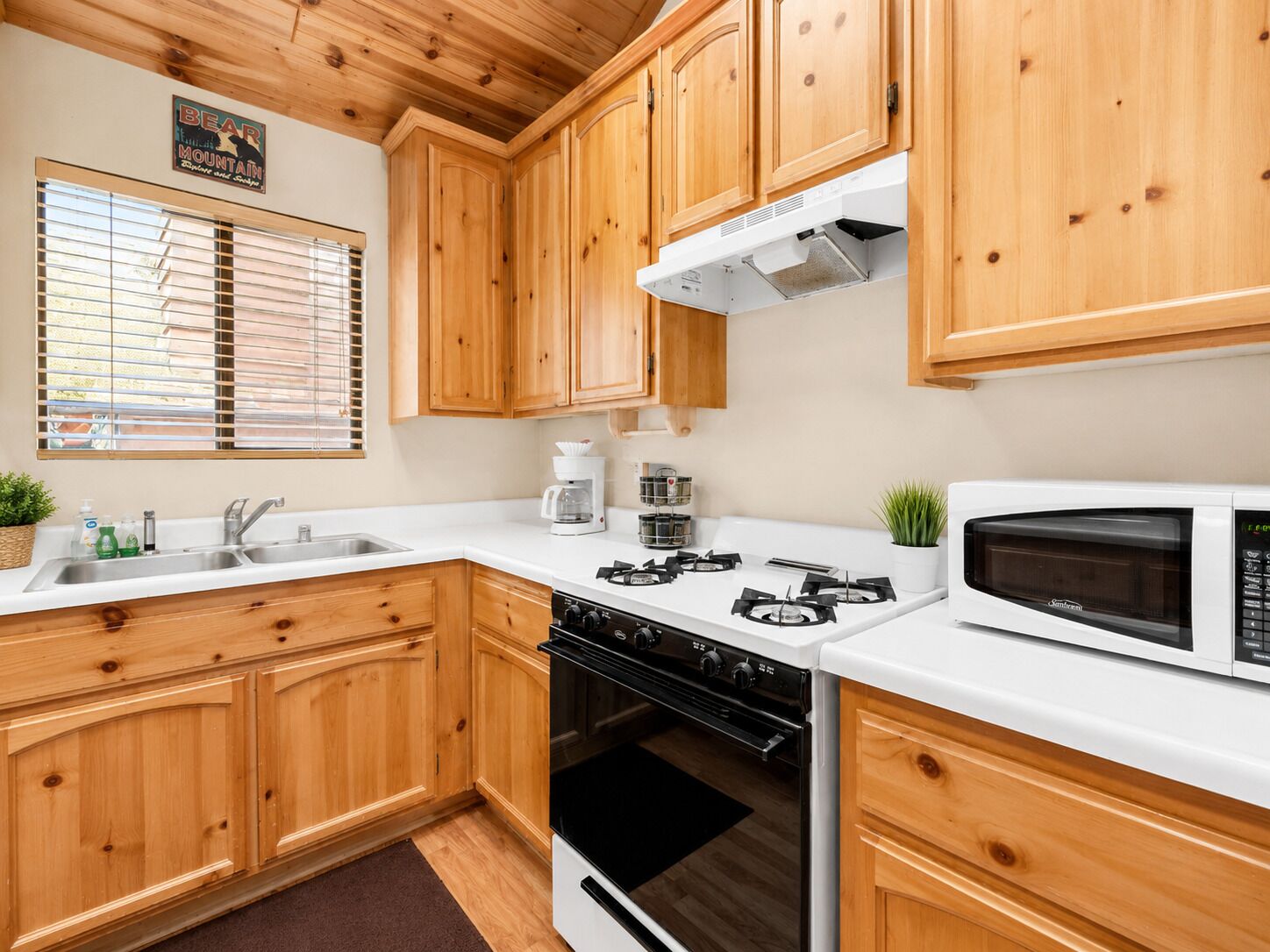 A kitchen with wooden cabinets, a gas stove, a microwave, and a coffee maker.