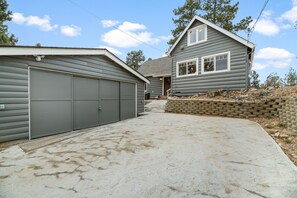 A two-story house with a garage, a front porch, and a stone retaining wall.