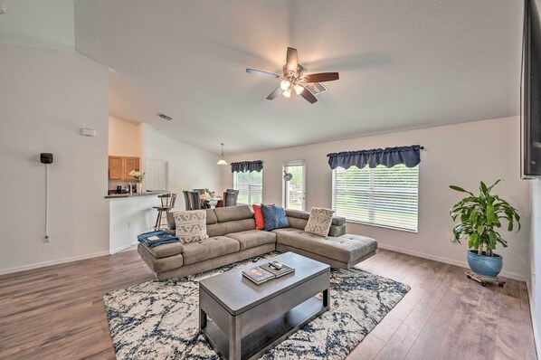A spacious living room with a sectional sofa, a coffee table, and a ceiling fan.