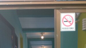 A hallway with a no-smoking sign, a door with a glass panel, and a wall with a sign indicating room rates. - Ilha Azul Hospedagem (Florianópolis)