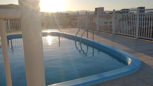A rooftop pool with a metal ladder and a white fence. - Ilha Azul Hospedagem (Florianópolis)