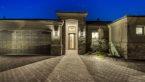 A two-story house with a garage, stone facade, and a well-lit entrance.