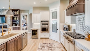 A modern kitchen with white cabinets, stainless steel appliances, and a built-in oven.