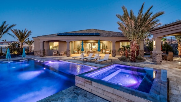 A modern house with a swimming pool, outdoor seating, and a patio area.