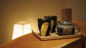 A wooden table with a ceramic mug and two cups on a coaster.