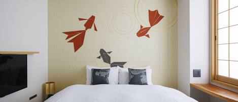 A hotel room with a bed, a TV, a window, and a wall with decorative leaf patterns.