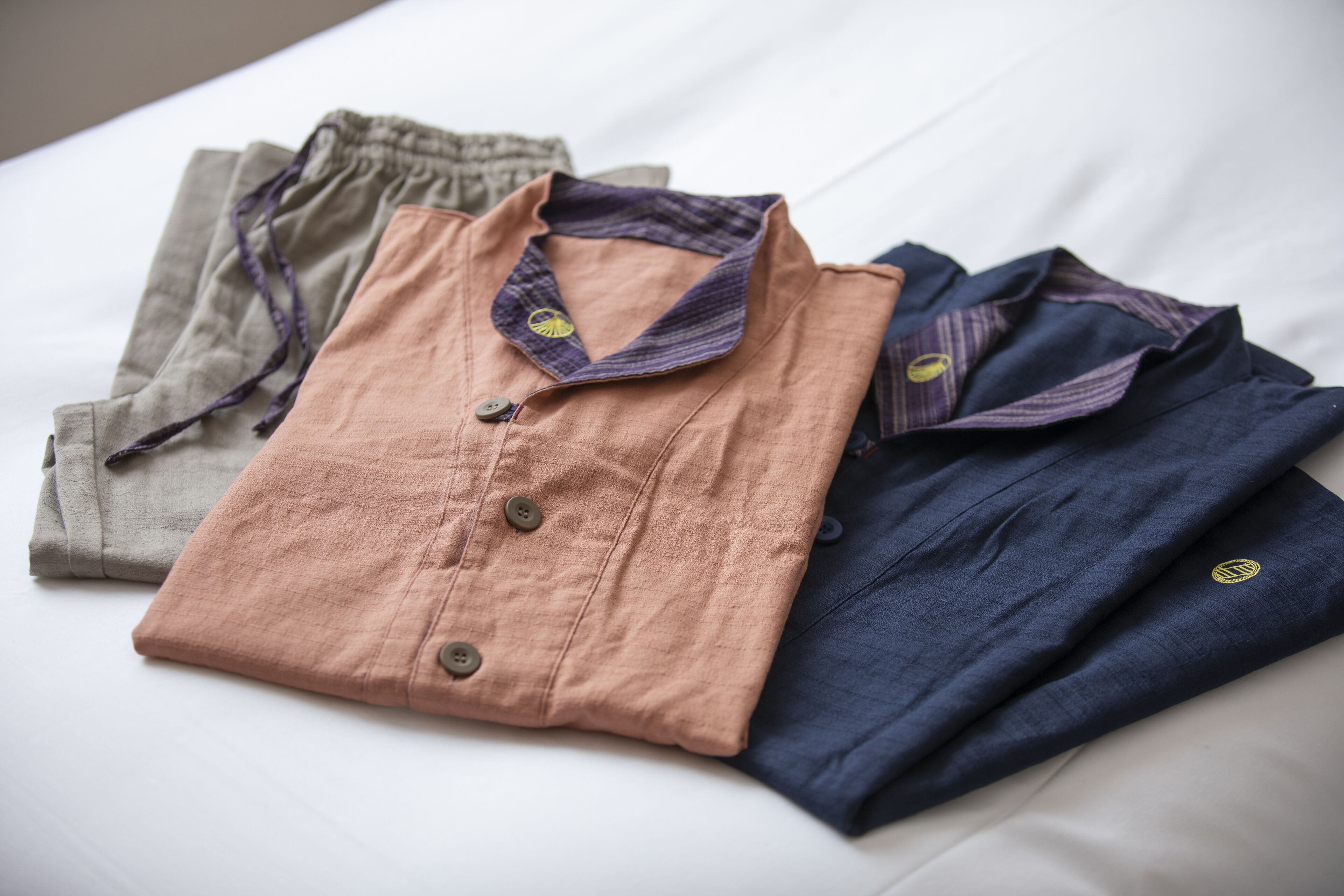 A neatly folded set of shirts on a bed.