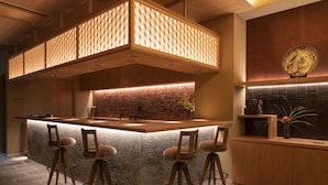 Una cocina moderna con una isla central, taburetes de bar y un elemento decorativo en la pared.