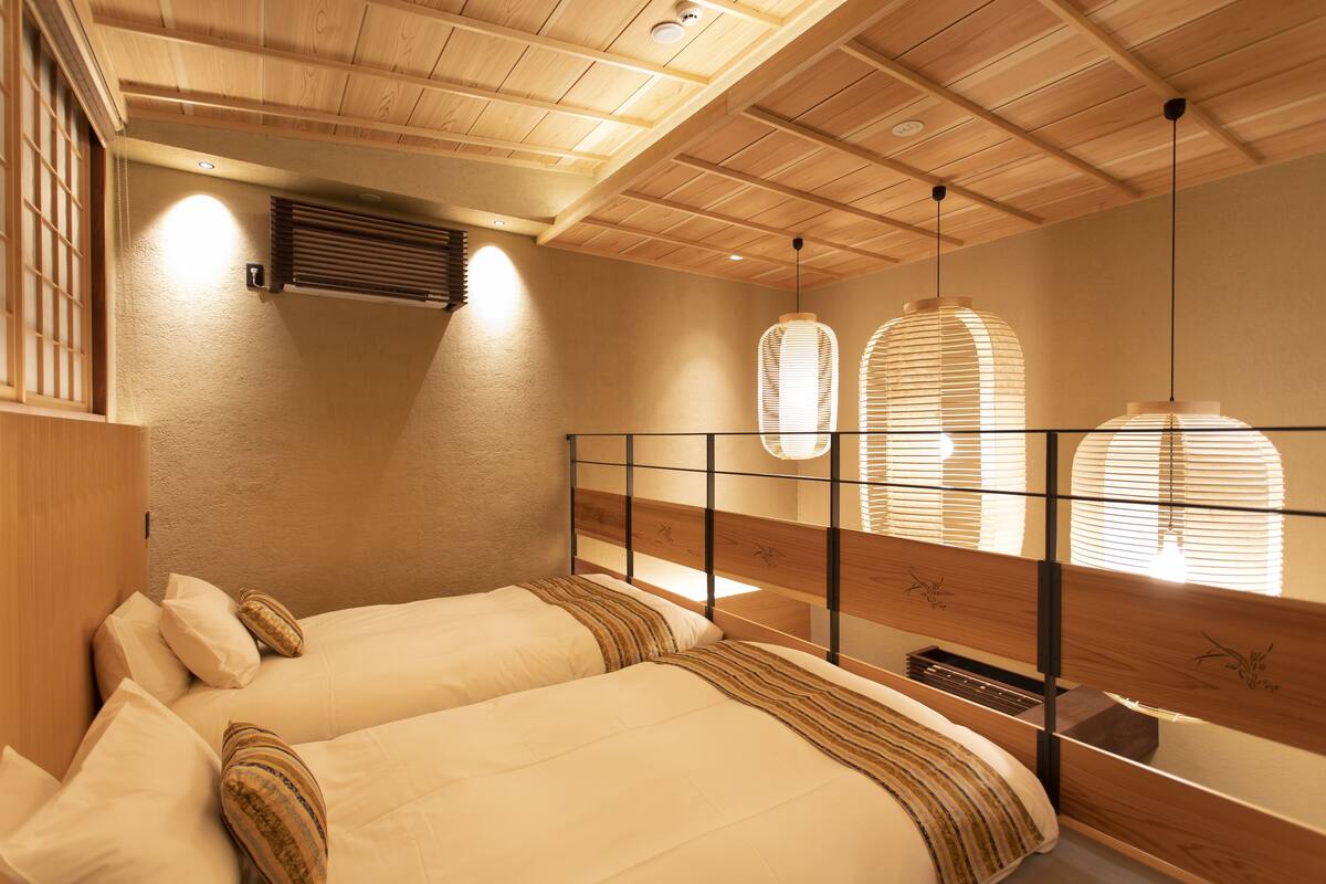 Un dormitorio con dos camas, vigas de madera en el techo y una ventana con persianas.