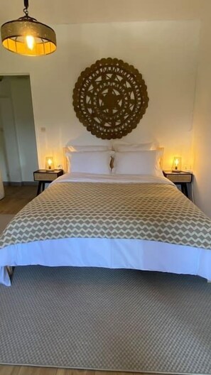 Relax in a spacious room with a large bed, two bedside tables, and a decorative wall hanging.