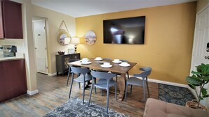 Un comedor con una mesa de madera dispuesta para cuatro personas, rodeado de sillas azules.