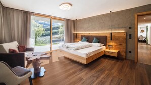 Une chambre moderne avec un grand lit, une tête de lit en bois, une table de chevet, un bureau et une vue sur l’extérieur.