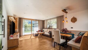 Un vaste espace de vie doté d’un plancher en bois, d’un canapé, d’une table à manger et d’un téléviseur.
