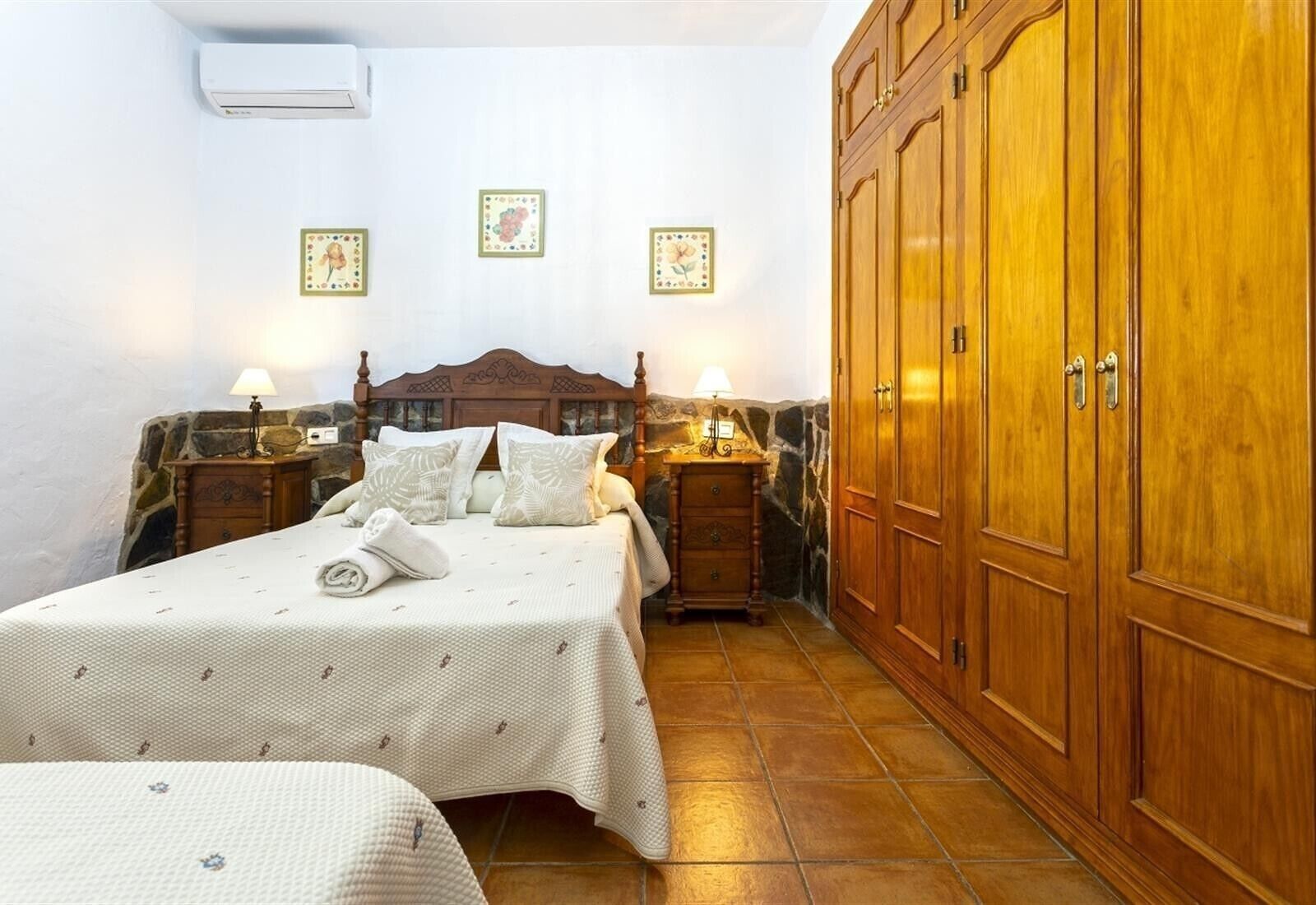 A bedroom with a bed, bedside tables, a wardrobe, and decorative wall art.