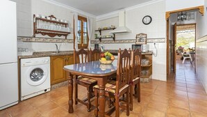 Una cocina con lavadora, una mesa de comedor con sillas y un reloj en la pared.