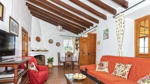Un salón acogedor con sofá, televisor, chimenea y vigas de madera en el techo.