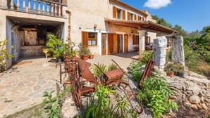 A stone building with a balcony, wooden shutters, and potted plants. - Holiday Home "Can Noble den Suau" with Pool, Hot Tub, Terraces & Garden (Pollensa)