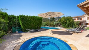 A swimming pool with a sun umbrella, lounge chairs, and a well-maintained garden. - Holiday Home "Can Noble den Suau" with Pool, Hot Tub, Terraces & Garden (Pollensa)