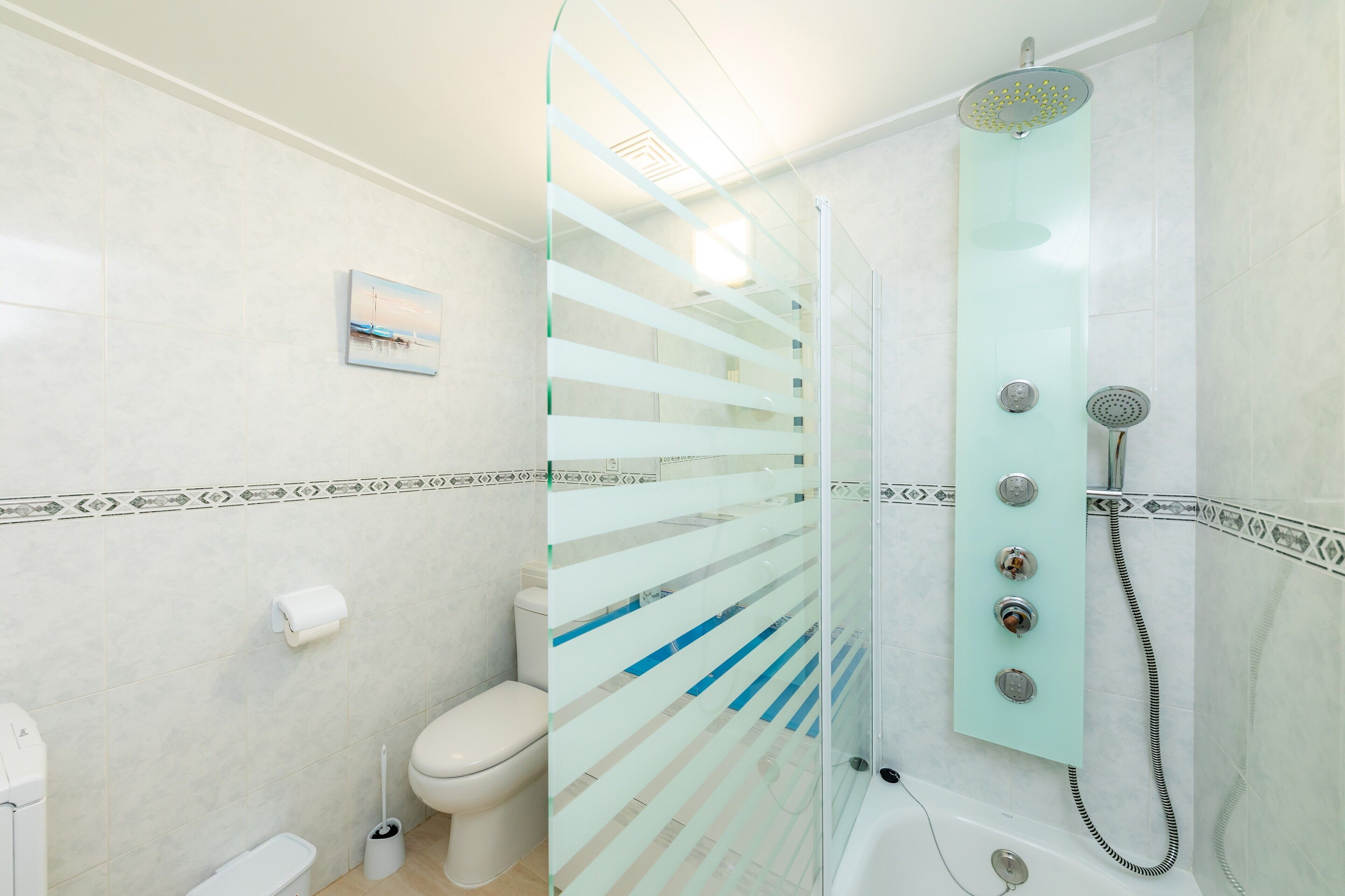 Een badkamer met een douchecabine van glas, een toilet en een bidet.