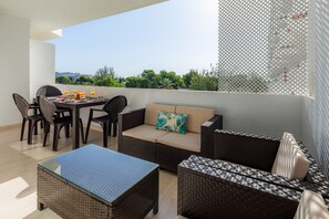 Een balkon met rieten meubels, een tafel met drankjes en een bank met een kussen.