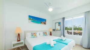 A hotel room with a bed, two bedside tables, a ceiling fan, a painting, a window with curtains, and a view of the outdoors. - Holiday Apartment "Alcudia Sea" with Large Balcony, Pool View & Wi-Fi (Home Office) (Alcudia)