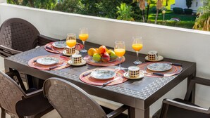 A dining table set with plates, glasses, and a fruit bowl, surrounded by chairs. - Holiday Apartment "Alcudia Sea" with Large Balcony, Pool View & Wi-Fi (Home Office) (Alcudia)