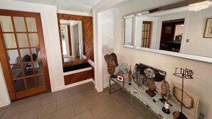 Un pasillo con piso de madera, un escaparate de vidrio con varios objetos y un espejo grande en la pared.