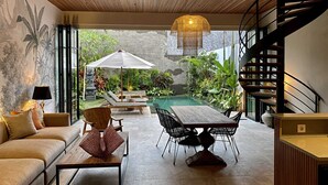 A modern interior with a dining area, sofa, and staircase. - Luxury Private Loft, 2 BR, Canggu With Staff (Canggu)