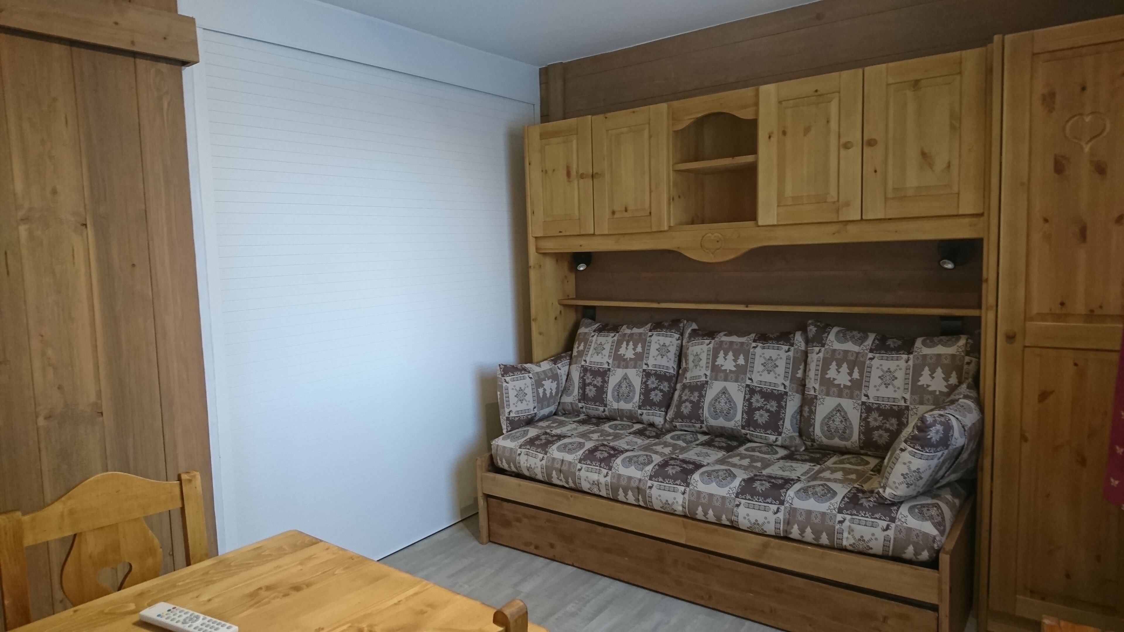 Un divano in legno con cuscini decorati, un tavolino con un telecomando e mobili in legno con un motivo a cuore.